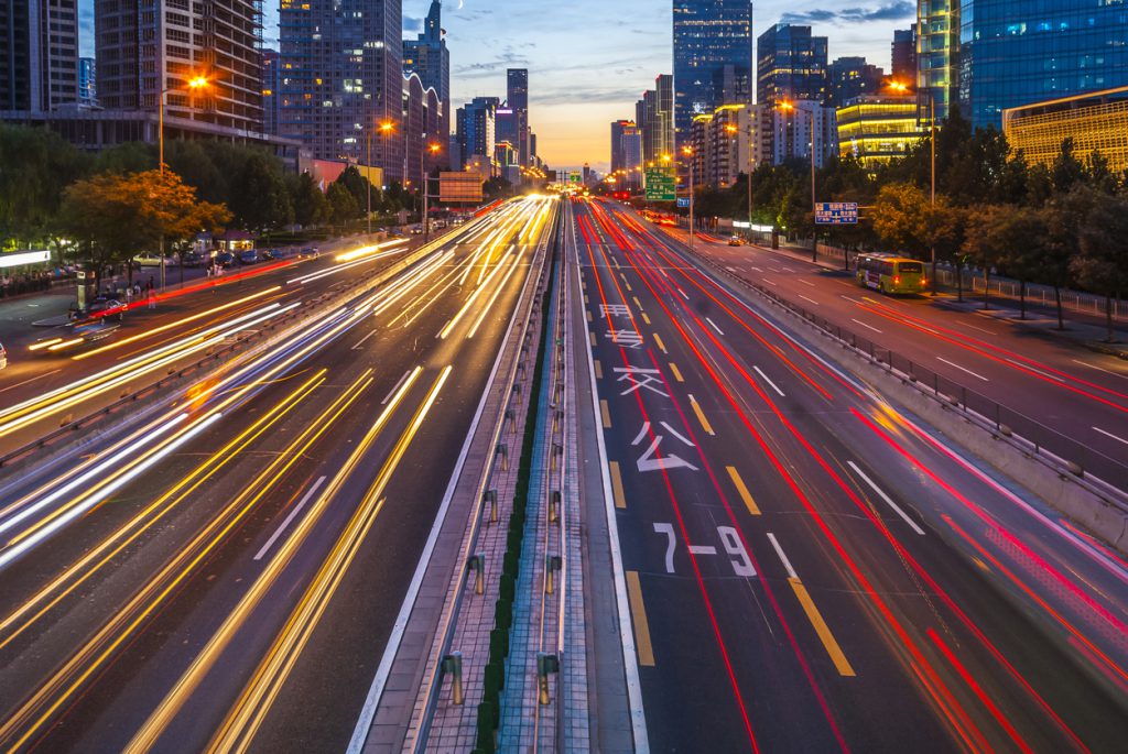 Long exposure of traffic in curve with red and white trails of light.