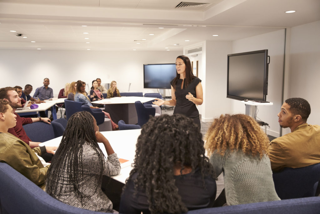 Female teacher addressing university students in a classroom Female teacher addressing university students in a classroom