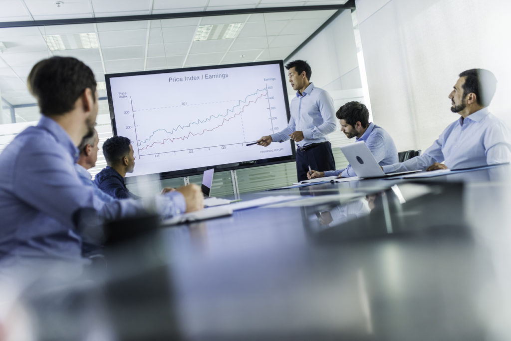 Business presentation Man of asian ethnicity talking to a group of businessmen and explaining an investment opportunity chart.