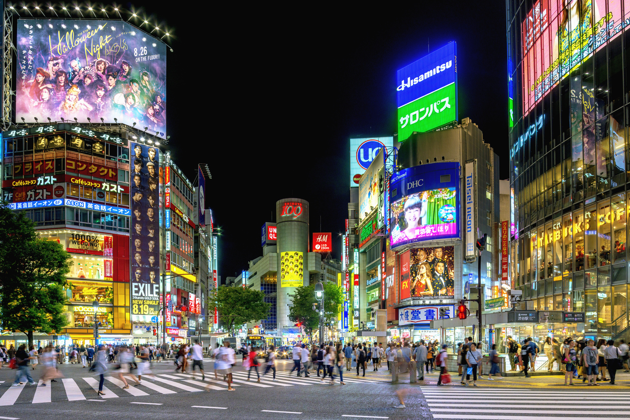 People crossing the famous Shibuya crossing in Tokyo at night.