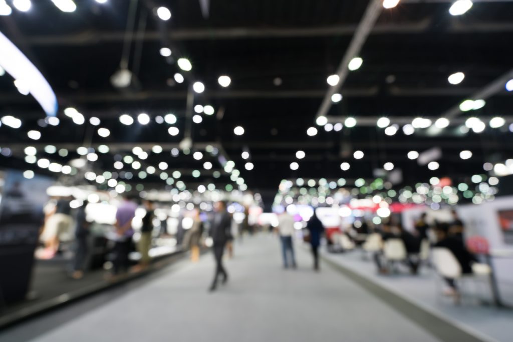 Blurred, defocused background of public exhibition hall. Business tradeshow or stock market, organization or company event, commercial trading fair, or shopping mall marketing advertisement concept