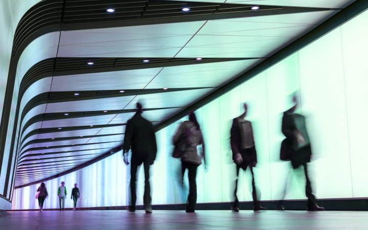 Businesspeople walking along the illuminated lightwall corridor, connecting One Pancras Square with King's Cross underground station in London, pedestrian tunnel in Kings Cross station, London, UK, England.