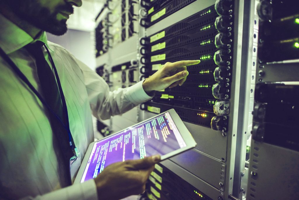 Handsome man is working in data centre with tablet. Handsome man is working in data centre with tablet.IT engineer specialist in network server room.Running diagnostics and maintenance.Technician examining server in big data center full of rack servers