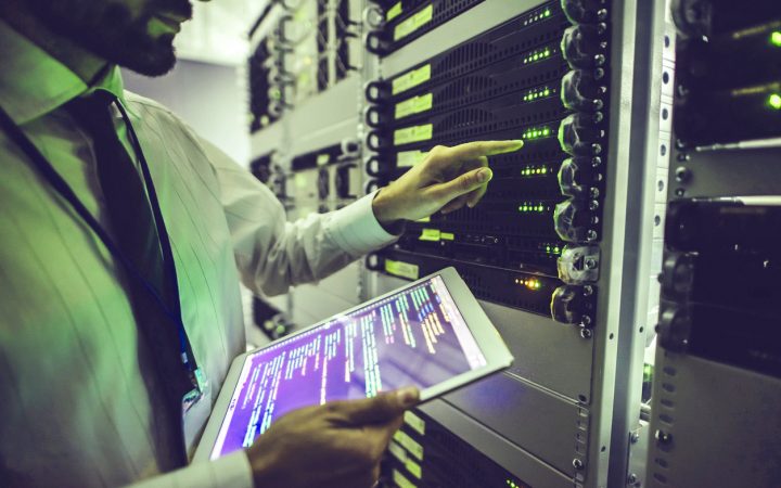 Handsome man is working in data centre with tablet. Handsome man is working in data centre with tablet.IT engineer specialist in network server room.Running diagnostics and maintenance.Technician examining server in big data center full of rack servers