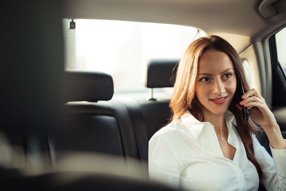 One woman, businesswoman talking on mobile phone in backseat of a car.