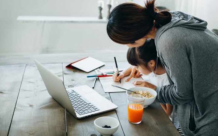 Young Asian mother served healthy breakfast on the table. Homeschooling her daughter and assists her with school work from home