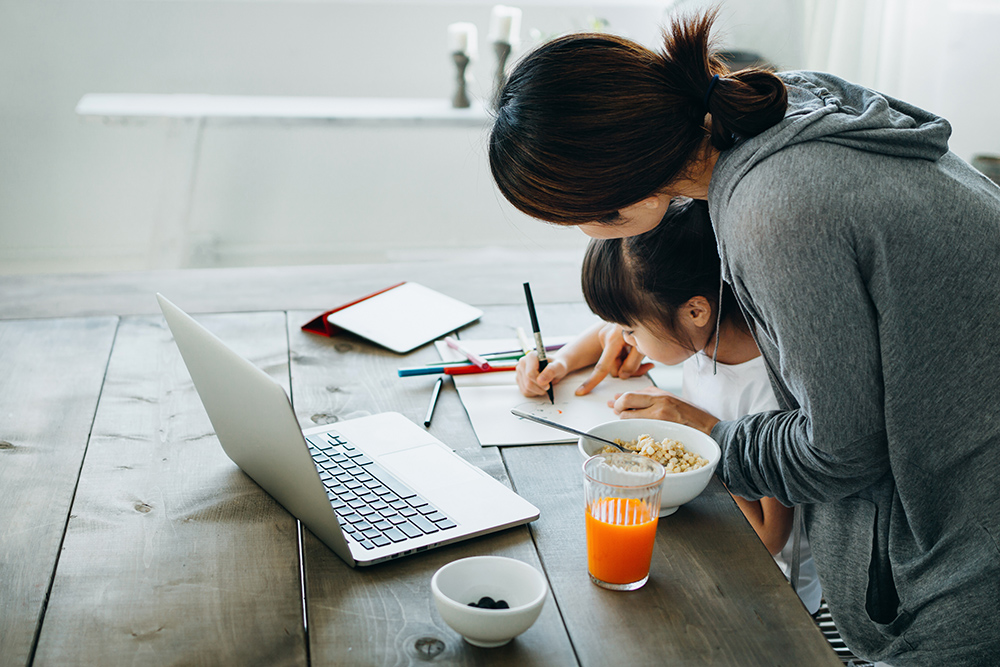 Young Asian mother served healthy breakfast on the table. Homeschooling her daughter and assists her with school work from home
