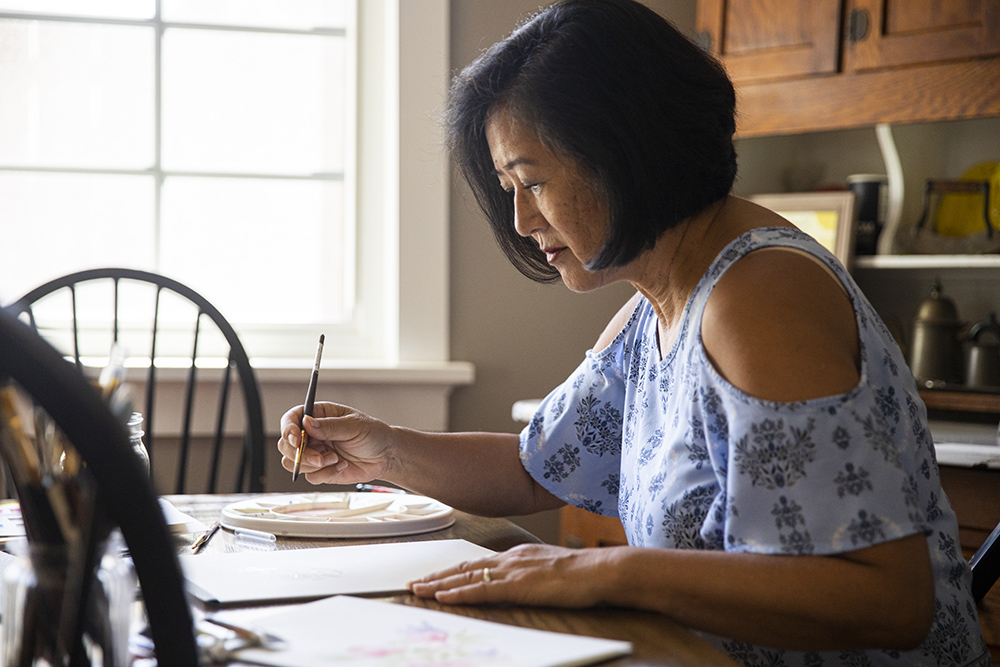 A senior Japanese woman watercolors at home