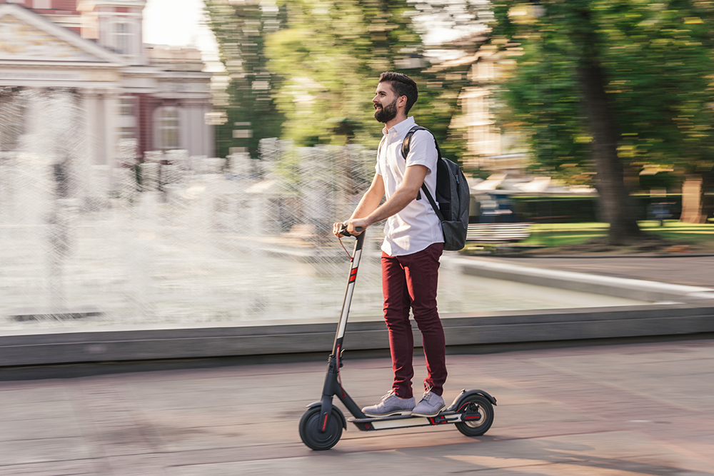 Confident young man riding electric scooter in the city