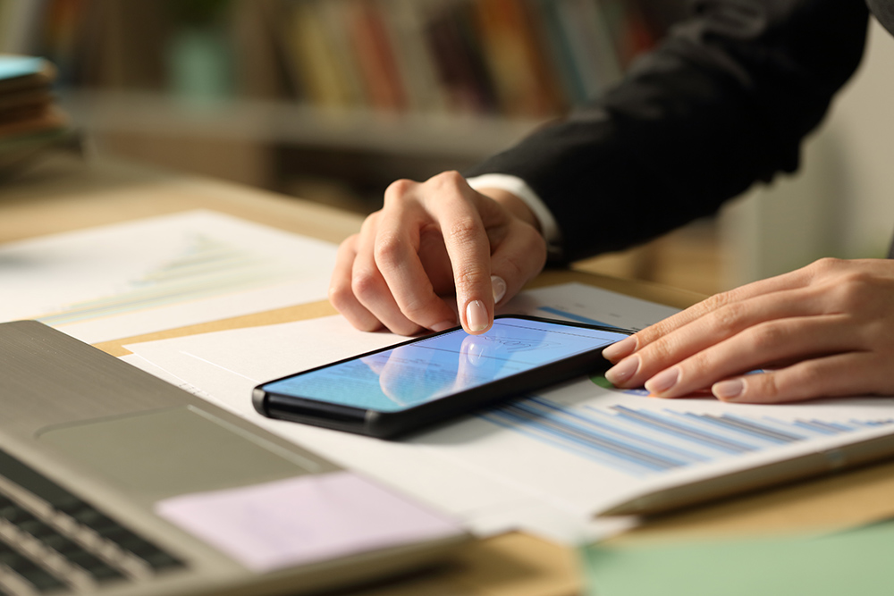 Close up of entrepreneur woman hands signing contract on smart phone with finger at night