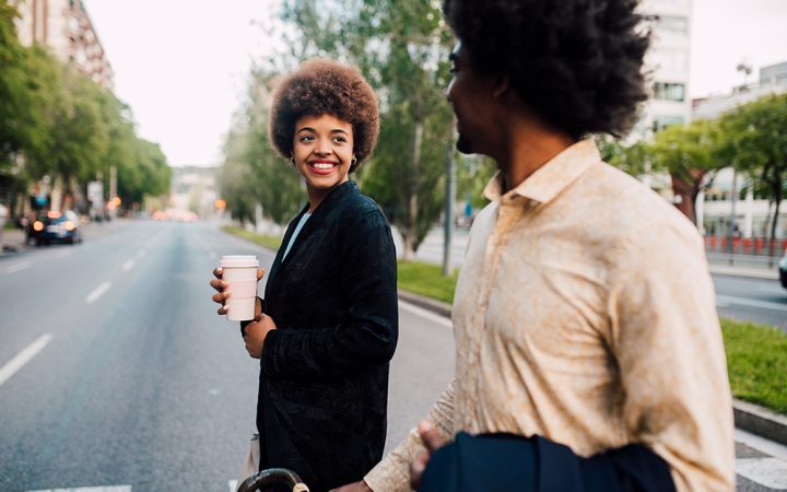 Two people chat in an urban district, enjoying their coffees