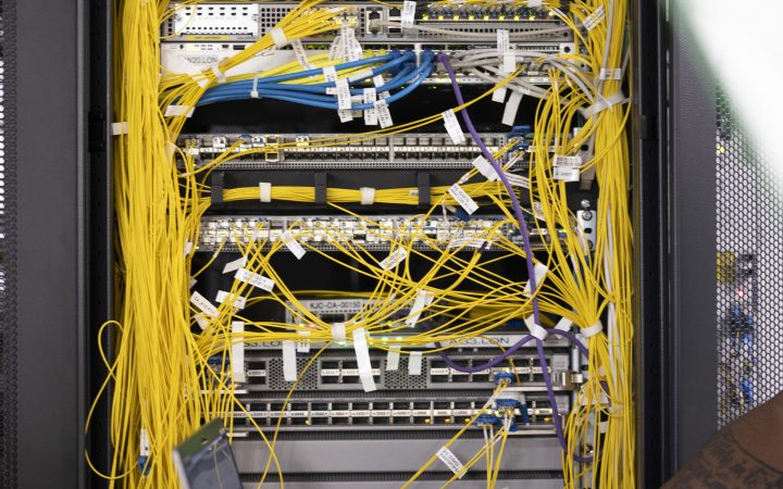 A man works on his laptop aside a server in a data centre