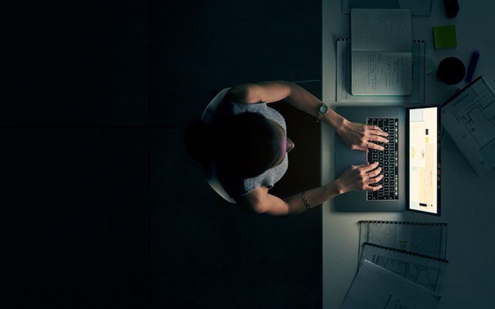 High angle shot of a young businesswoman using a laptop during a late night in a modern office