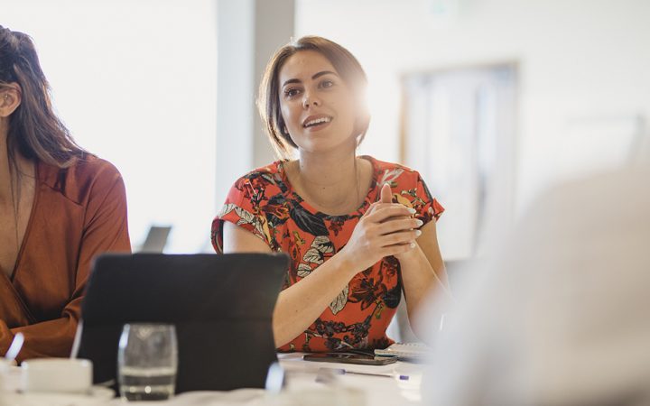 Confident young businesswoman listening carefully at conference table