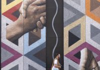 Hipster-looking man with a Colt bag walking past a Connectivity mural