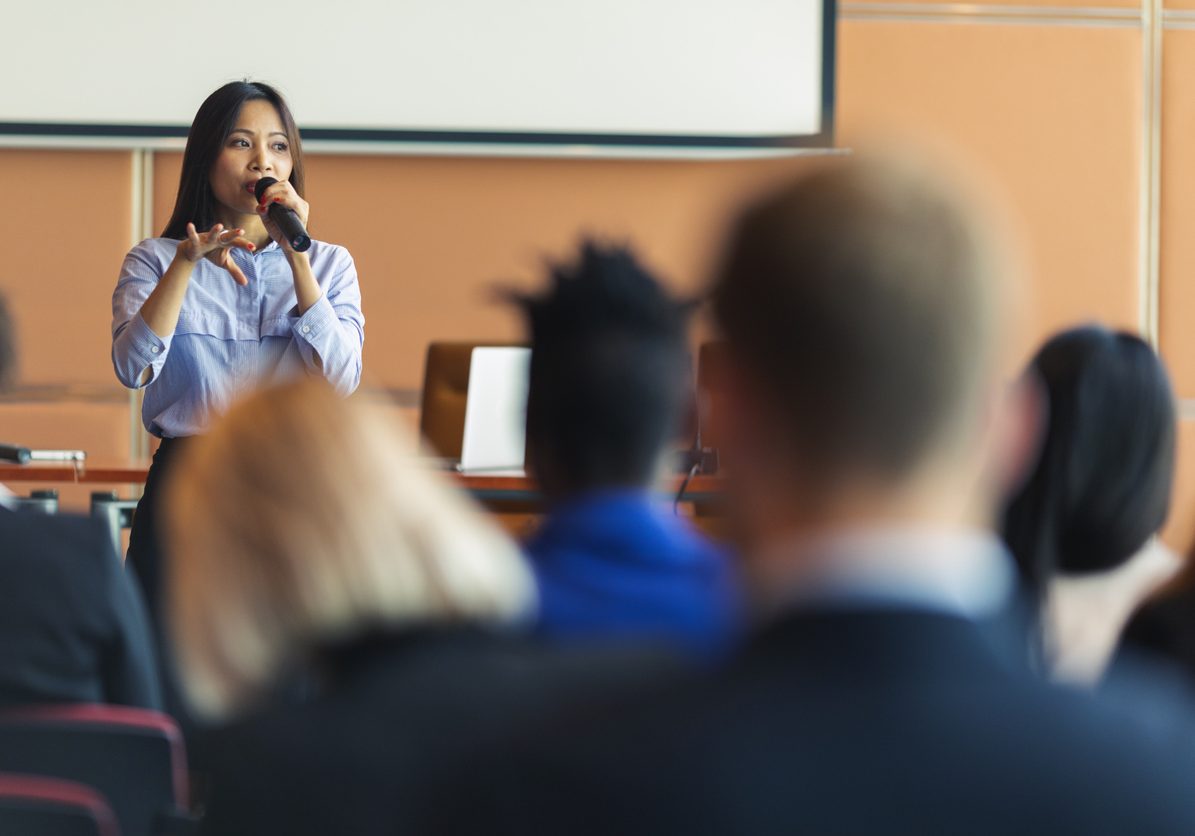 An Asian female presenter interacting with the audience at a business presentation in the board room