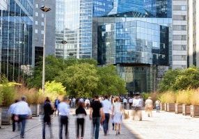 crowd of business people walking through financial district towards modern office building, La Defense, Paris, France