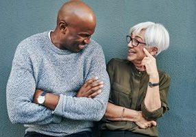 Shot of two cheerful mature businesspeople having a discussion while standing against a wall outdoors