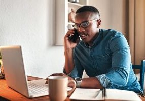 Cropped shot of a handsome young businessman sitting alone in his home office and talking on his cellphone