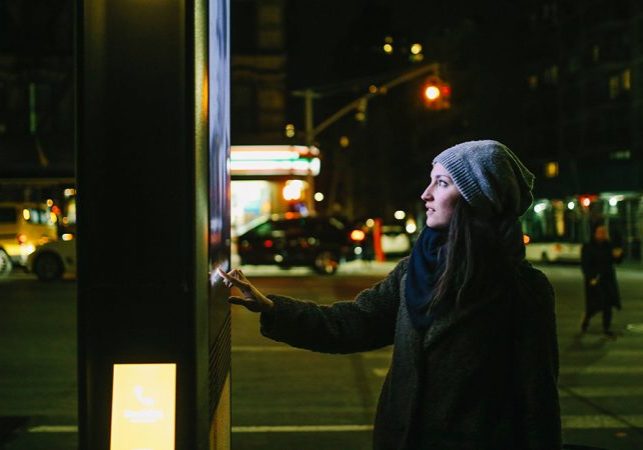 Young woman using interactive touch screen city display to check for information, New York City, USA.